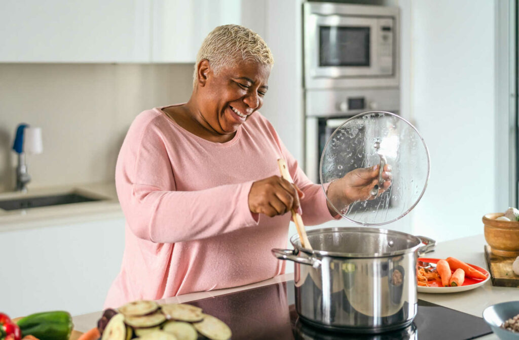 Happy senior woman makes a healthy vegetable soup.