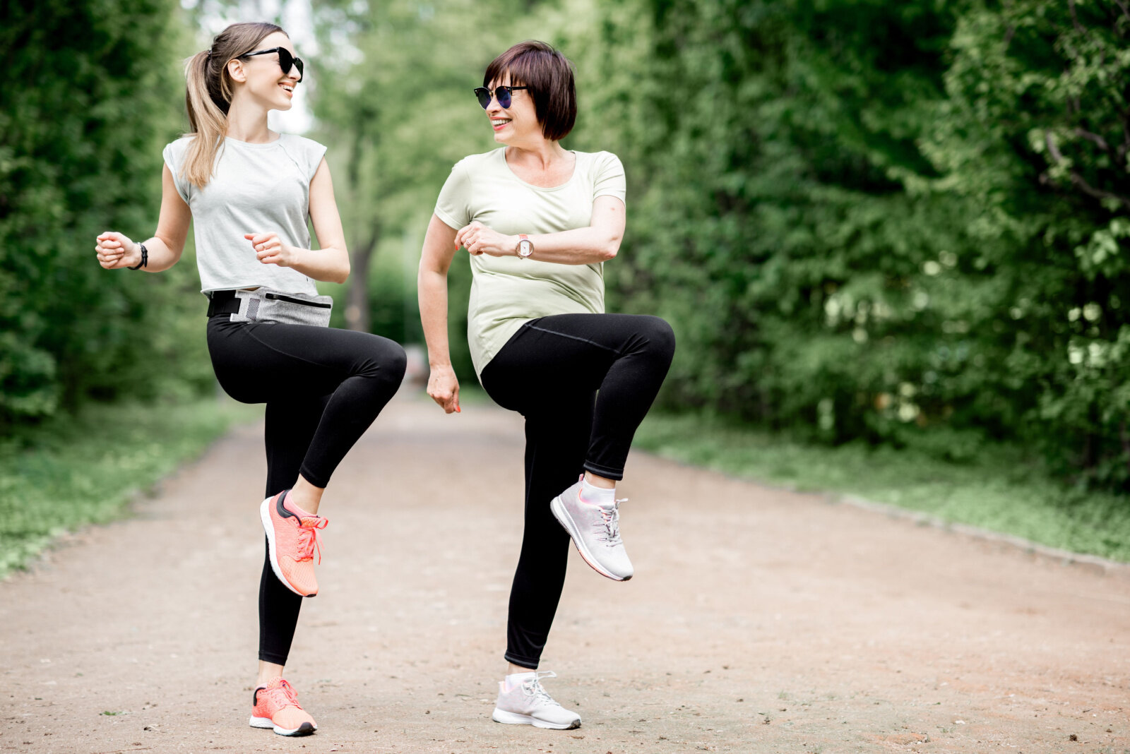 A daughter doing exercise outdoors with her mother with diabetes to keep her active and healthy.
