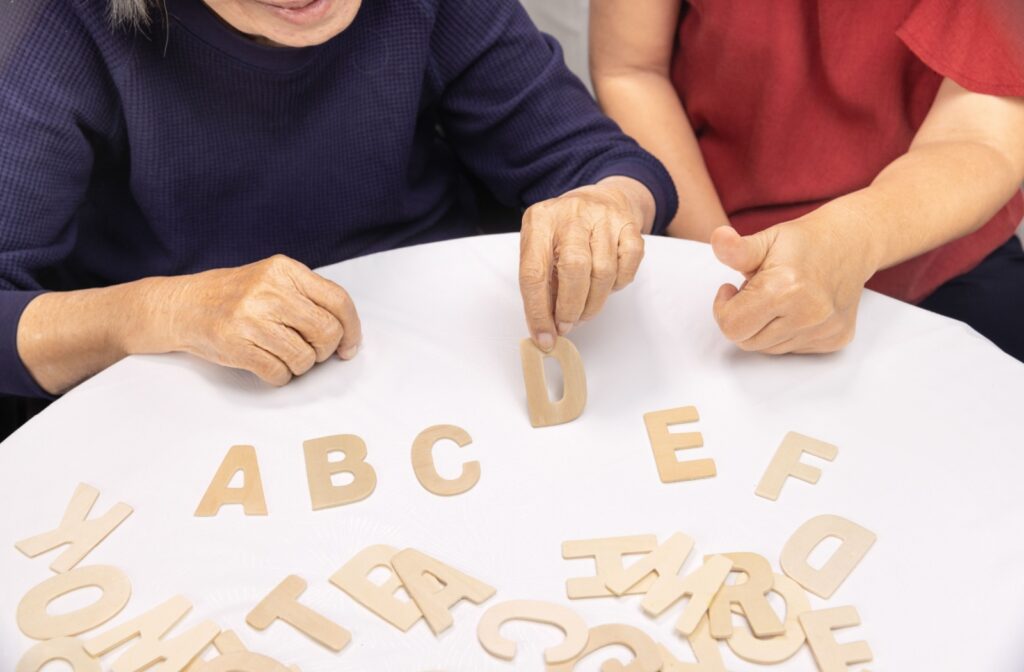 A close-up of 2 senior women's hands as they sort wooden letters into alphabetical order.