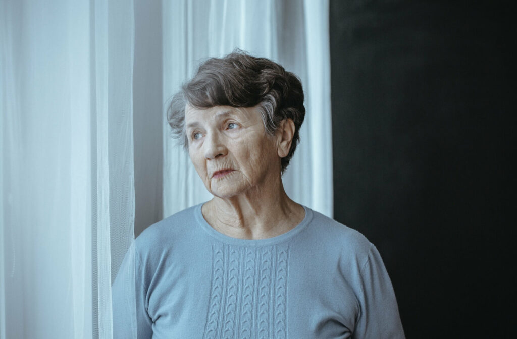 Senior woman with Alzheimer's disease, gazing out the window with a pensive expression