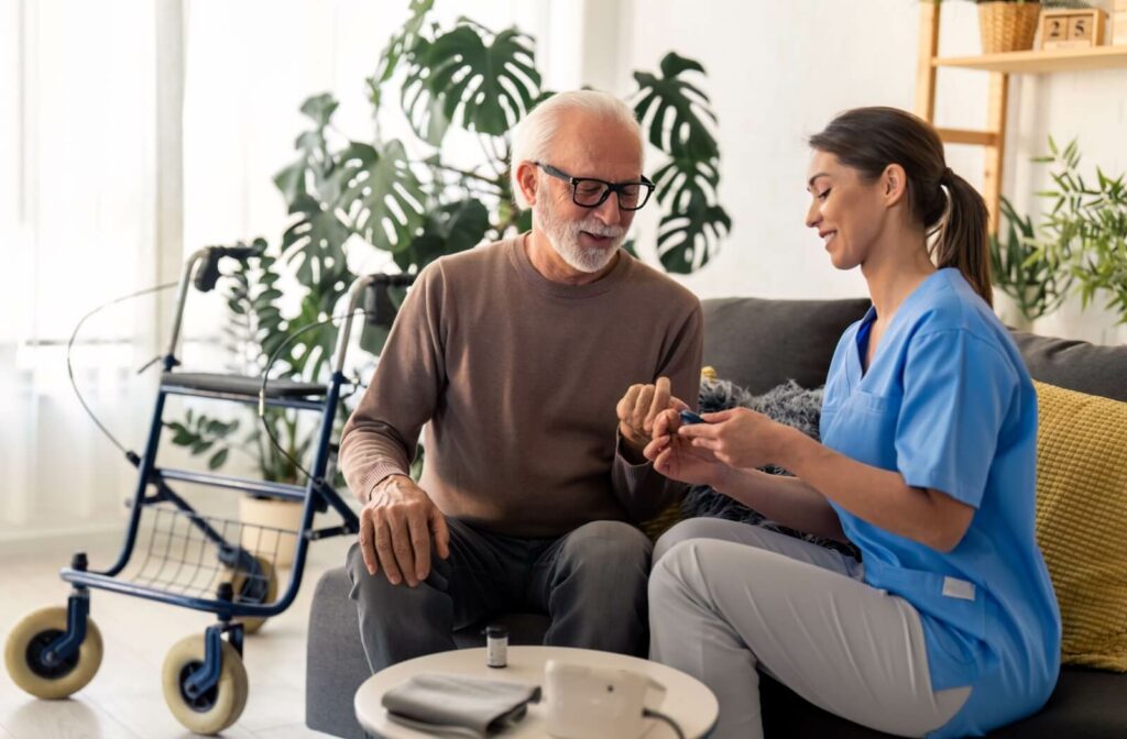 A nurse helps their elderly patient check their blood sugar levels by pricking their finger with a blood glucose meter.