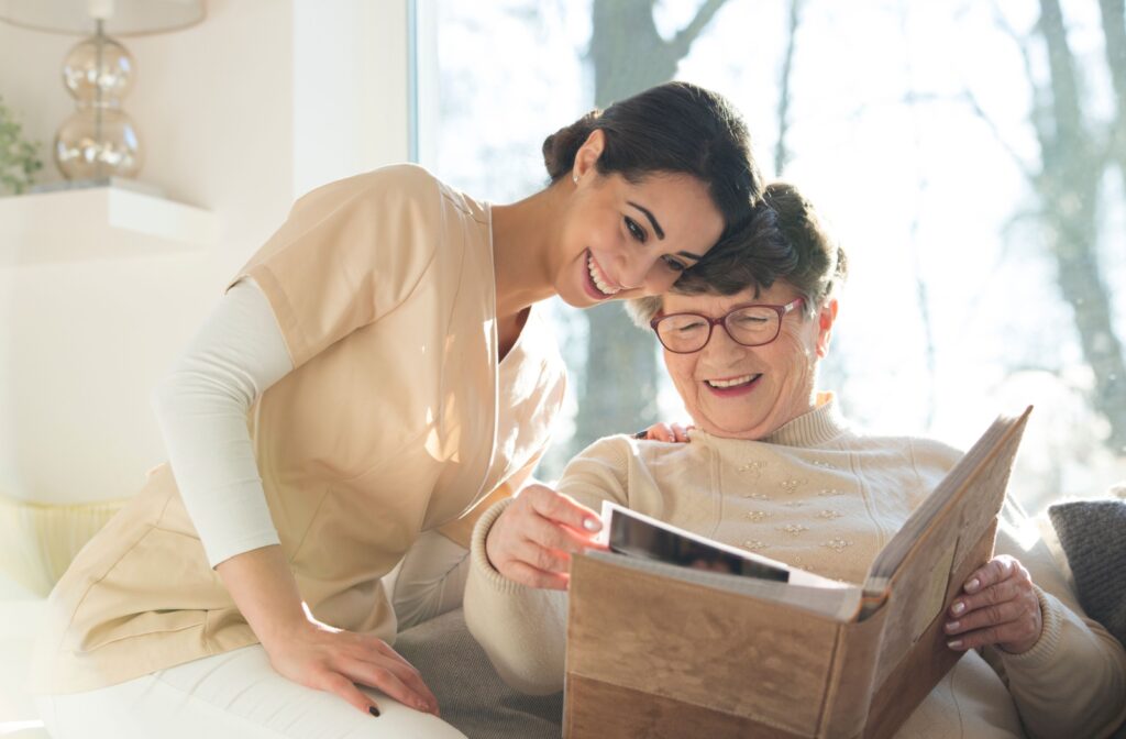 A smiling senior with dementia looks through a photo album from their life with a nurse while relaxing.