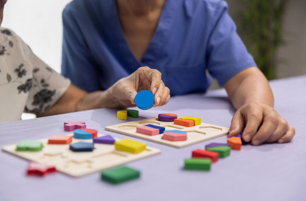 A nurse assists a memory care patient with a shape-based game meant to support memory skills.