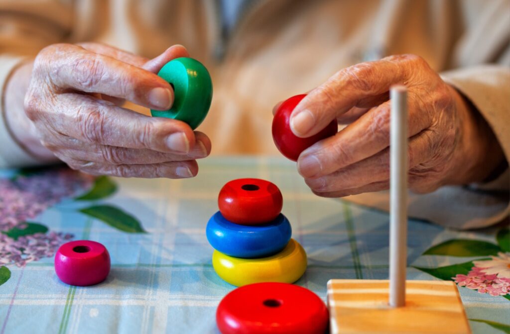 A close-up image of an older adult's hands working with wooden pieces in memory care.