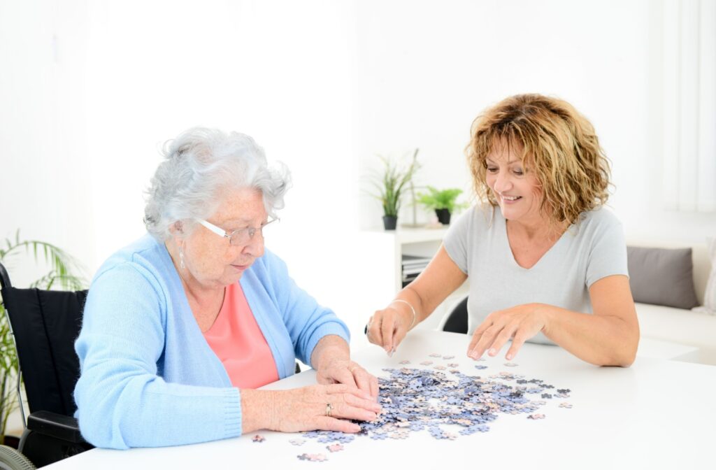 An adult child working on a puzzle with their parent at home.