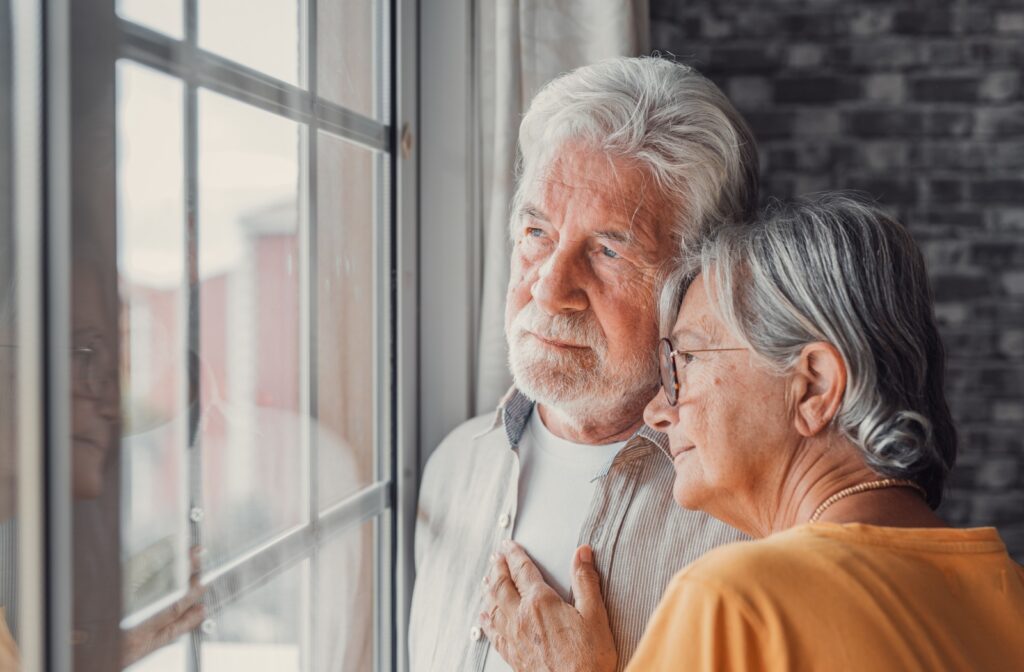 A cheerful older adult seated in a wheelchair shares a heartfelt moment with their companion.