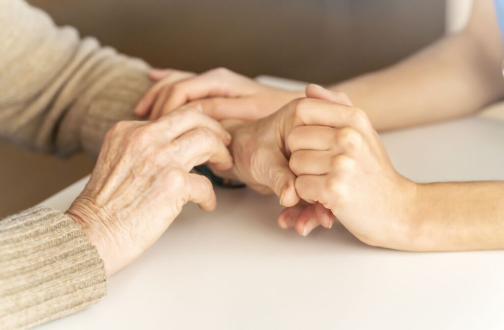 Young hands hold senior hands comfortingly after a dementia diagnosis.
