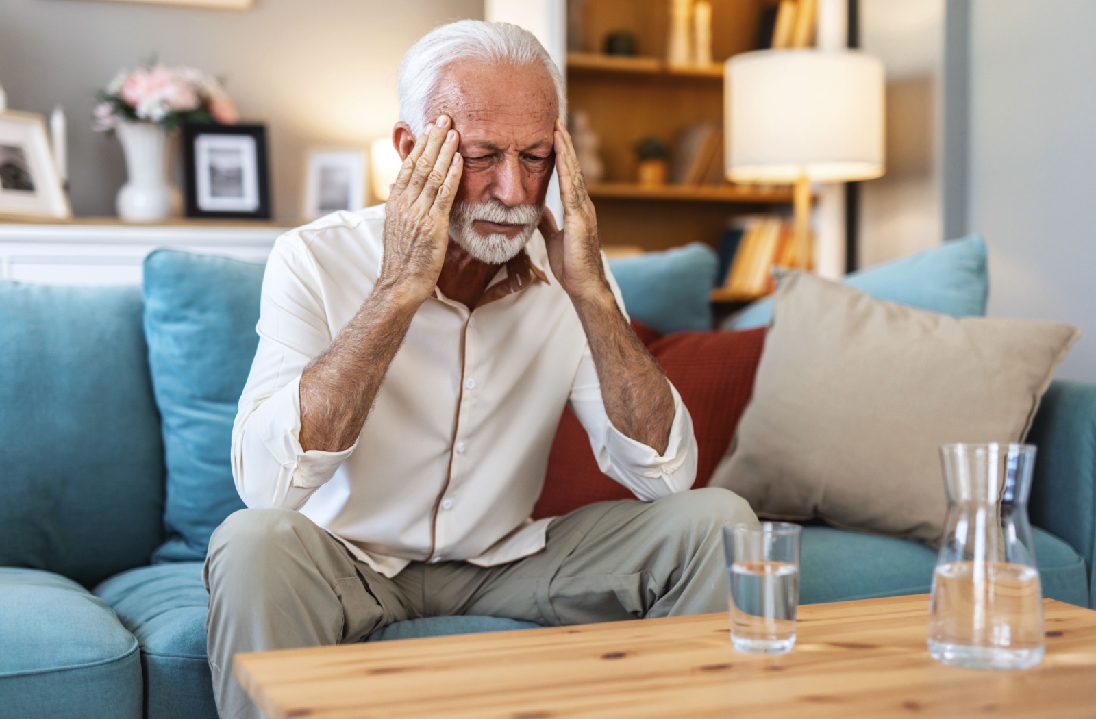 A senior looking frustrated, with their hands on their temples, struggling with brain fog.