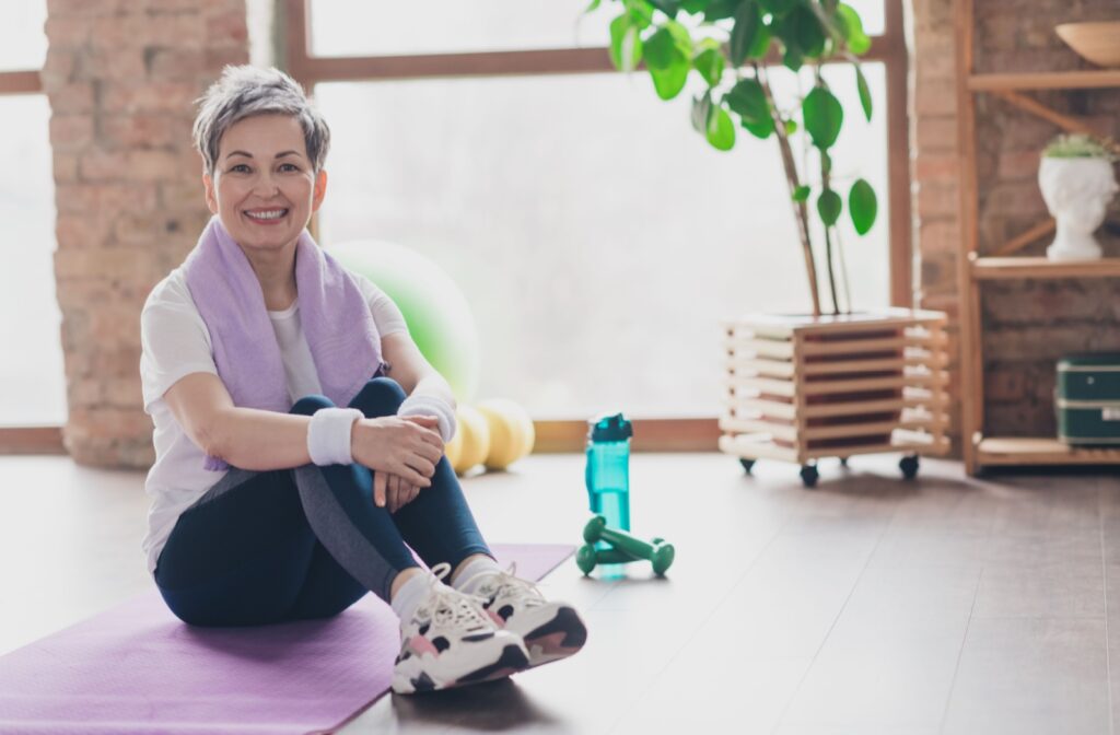 A senior sitting on a yoga mat, taking a break during exercise to help reduce symptoms of brain fog.
