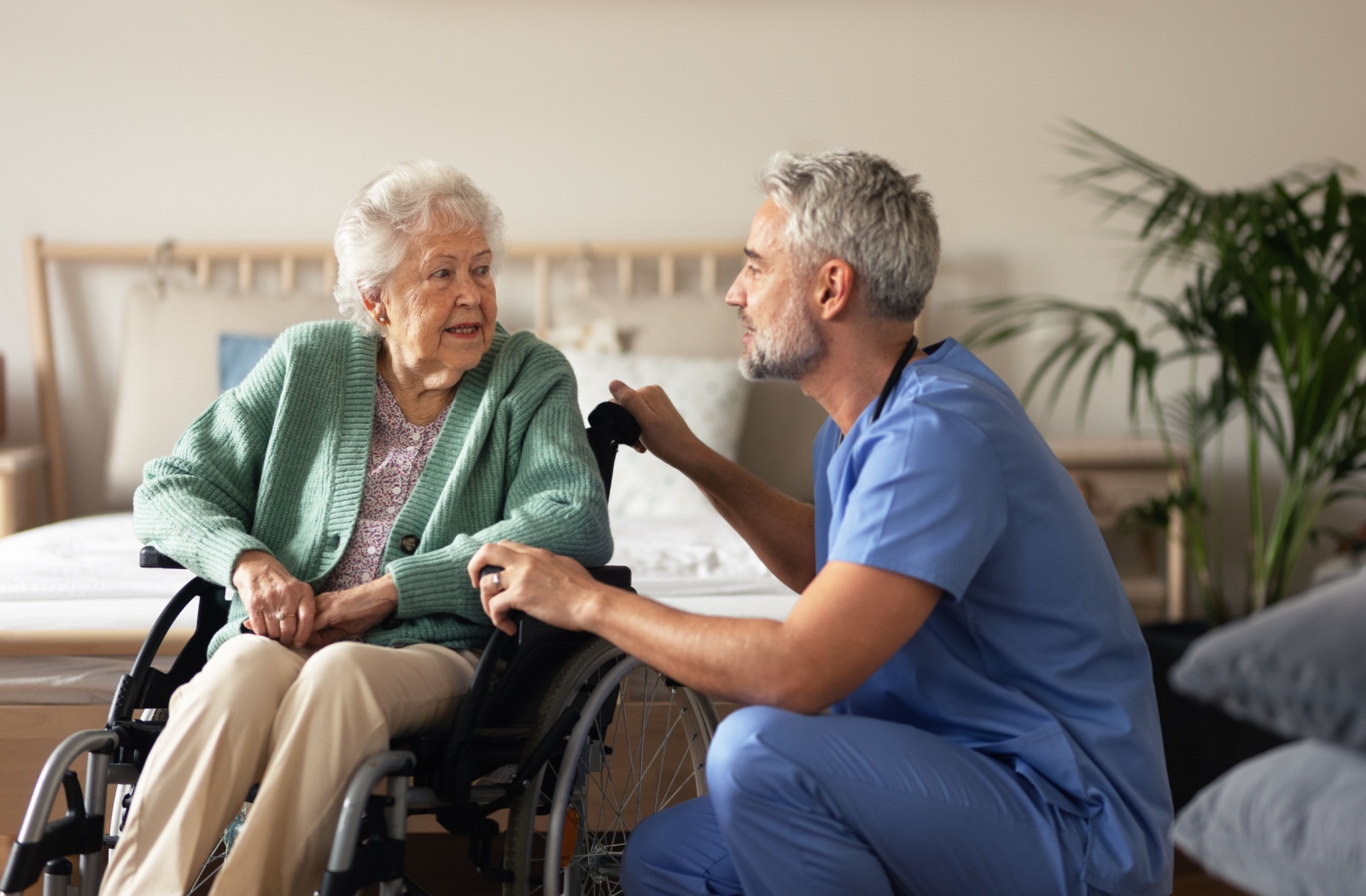 A male nurse speaking to an older female in an assisted living community.