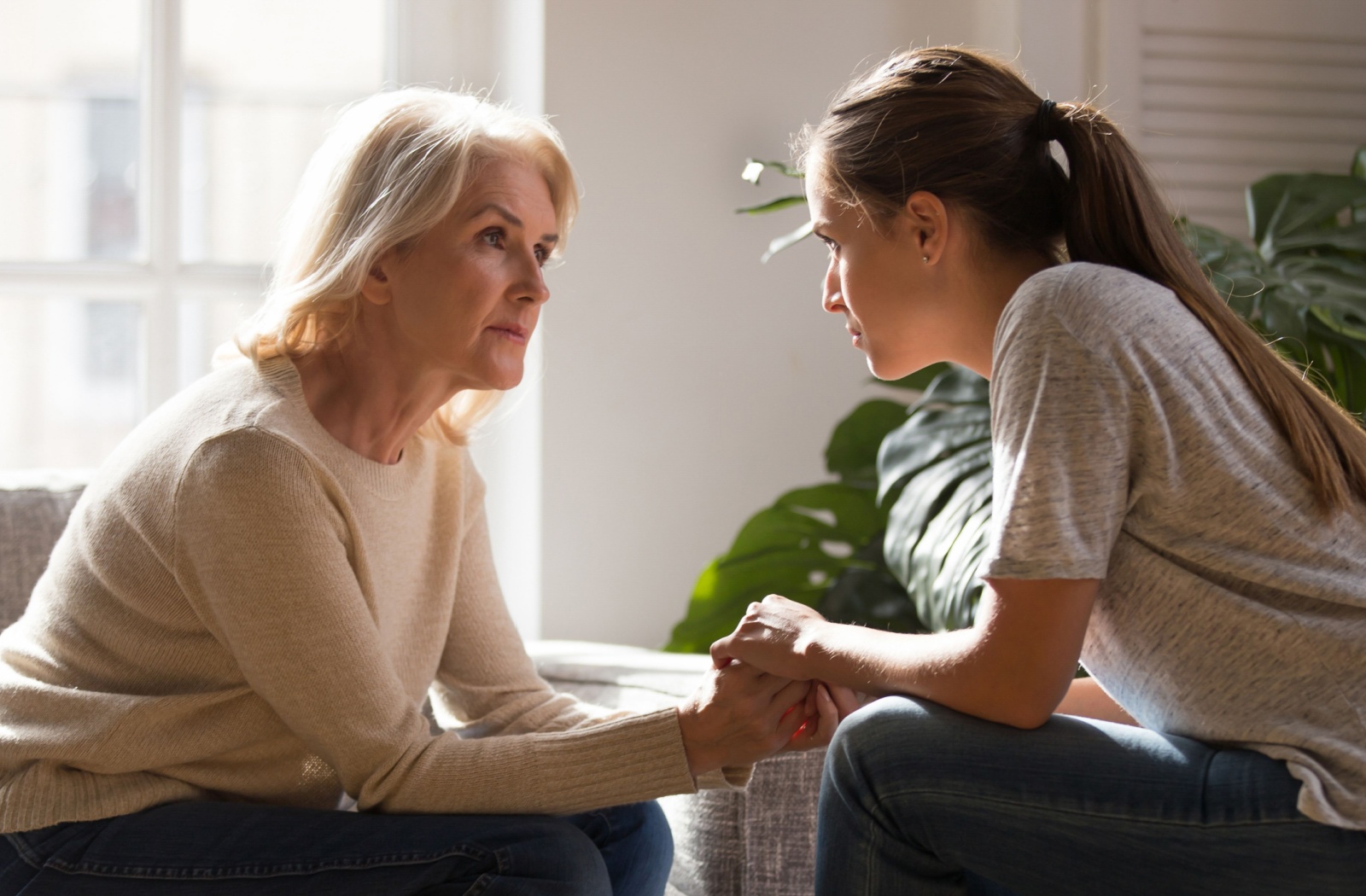 An adult holds hands with their senior parent while having a heart-to-heart talk about assisted living.