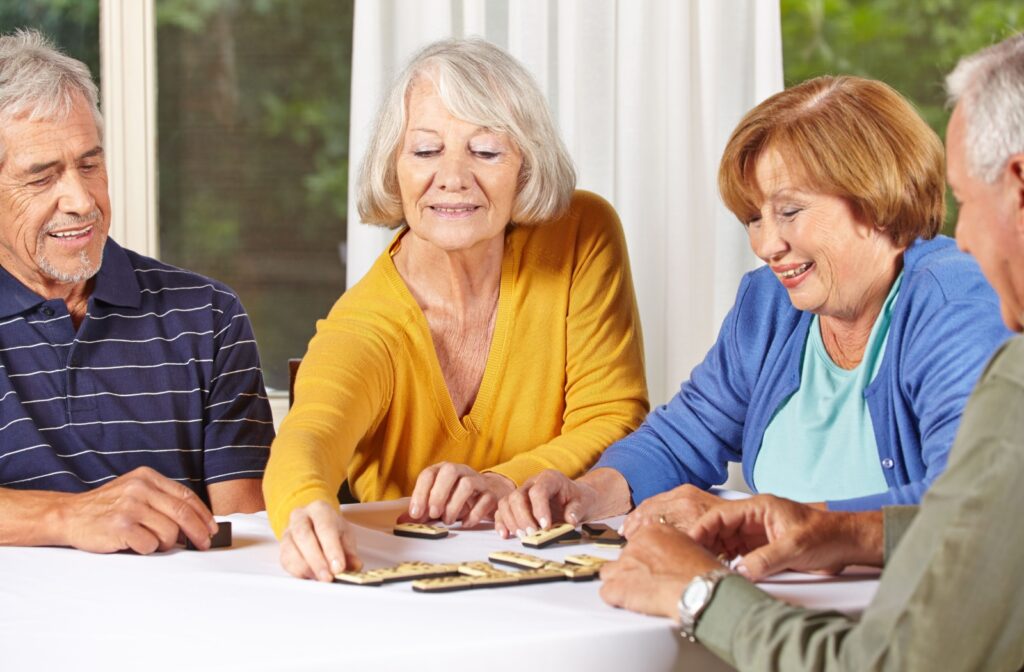 A group of seniors in an assisted living community plays dominoes together.