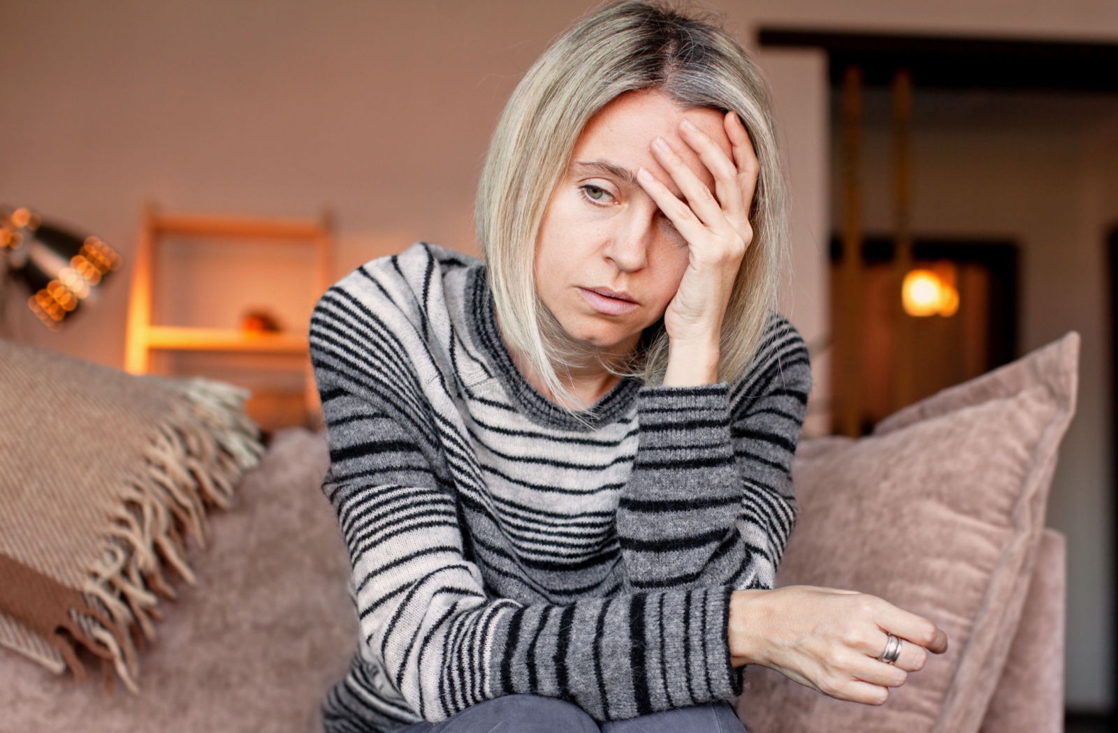 An adult child expresses stress from caregiver burnout, with their head in their hand.