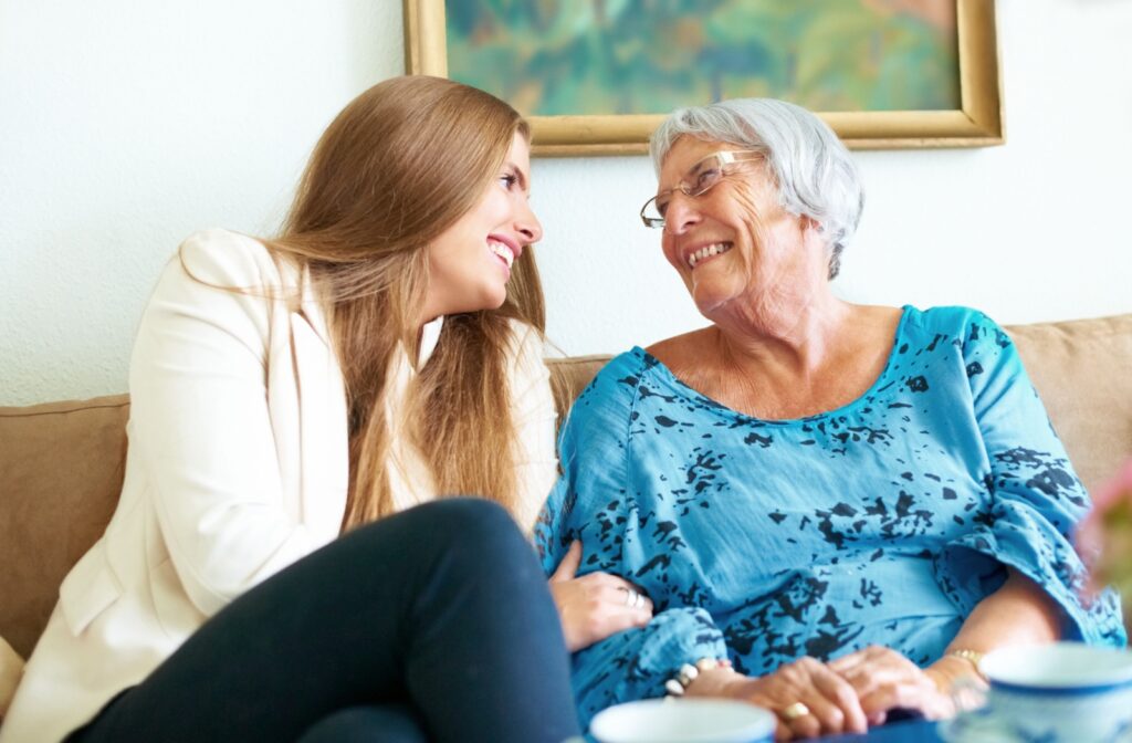 A senior sits and chats with their grandchild on a couch.